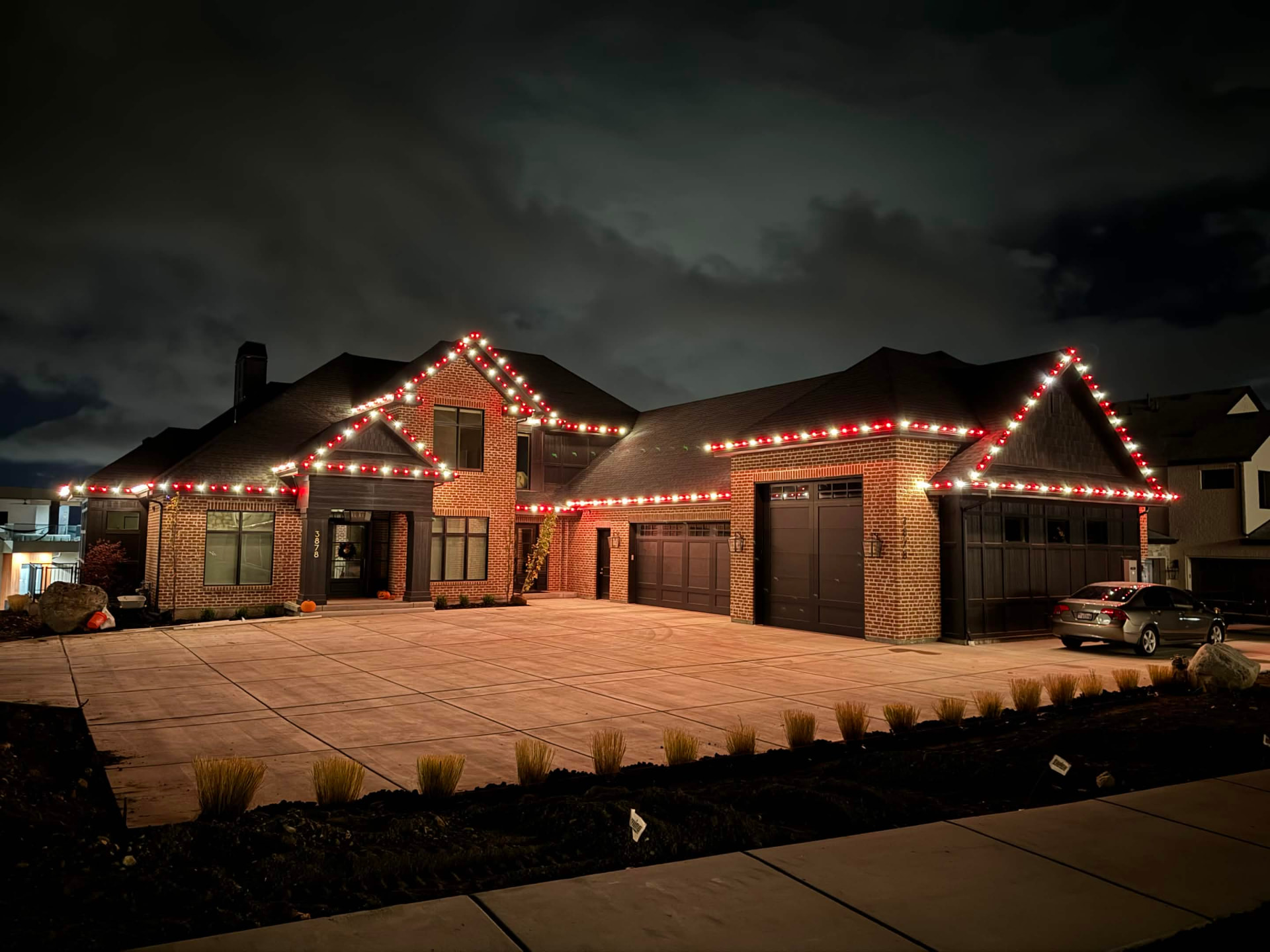 Large Utah brick estate illuminated with red and white holiday roofline lighting