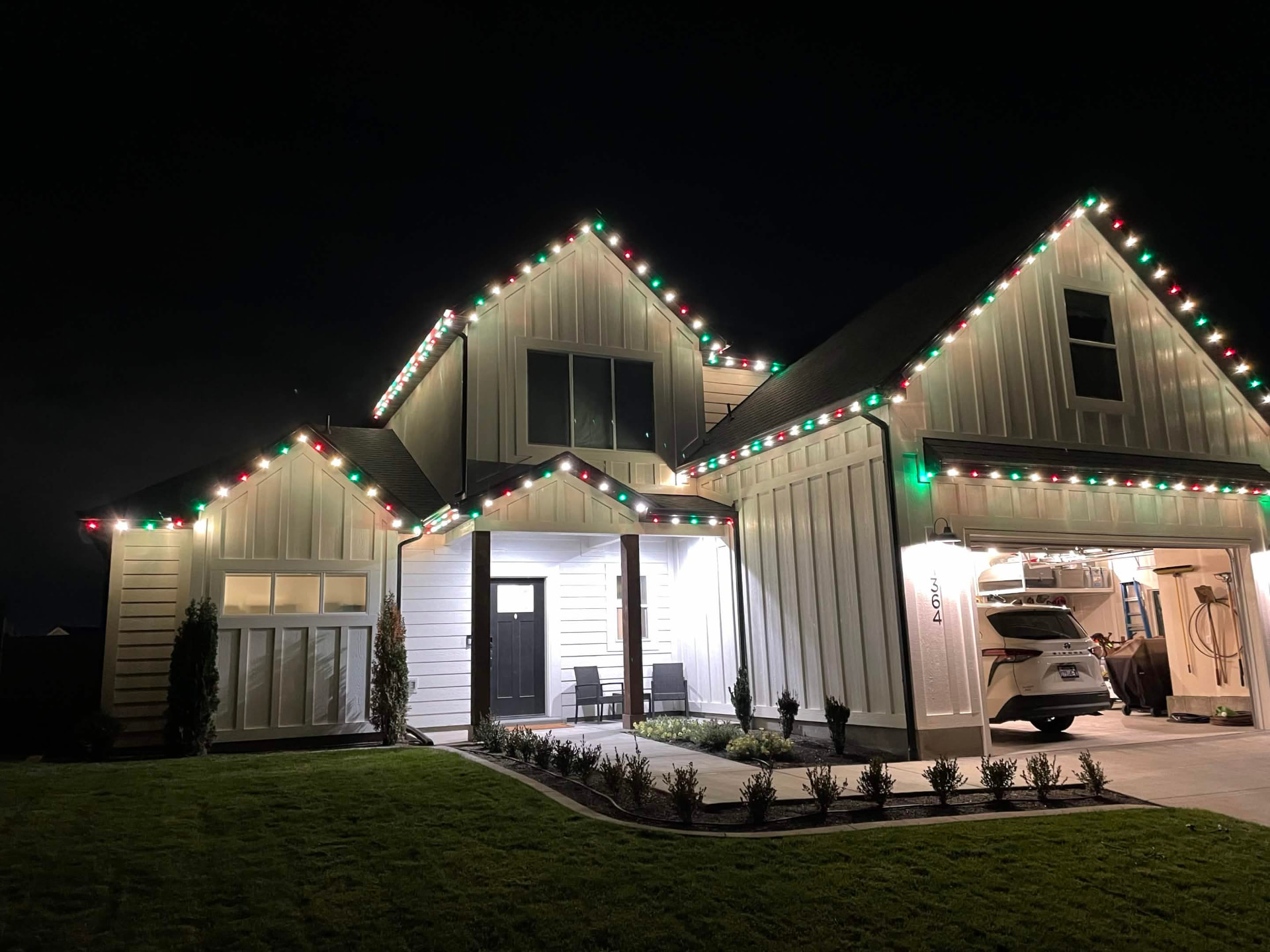 Utah farmhouse outlined in red and green C7 Christmas lights at night